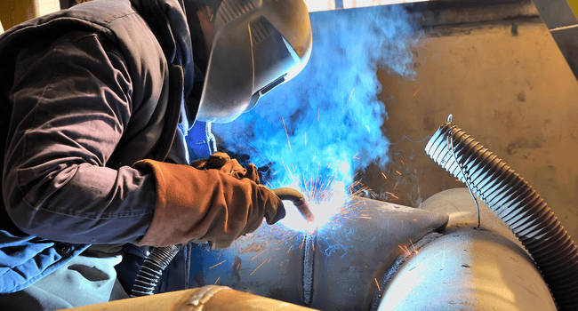 Soudeur en train de souder un tuyau en acier