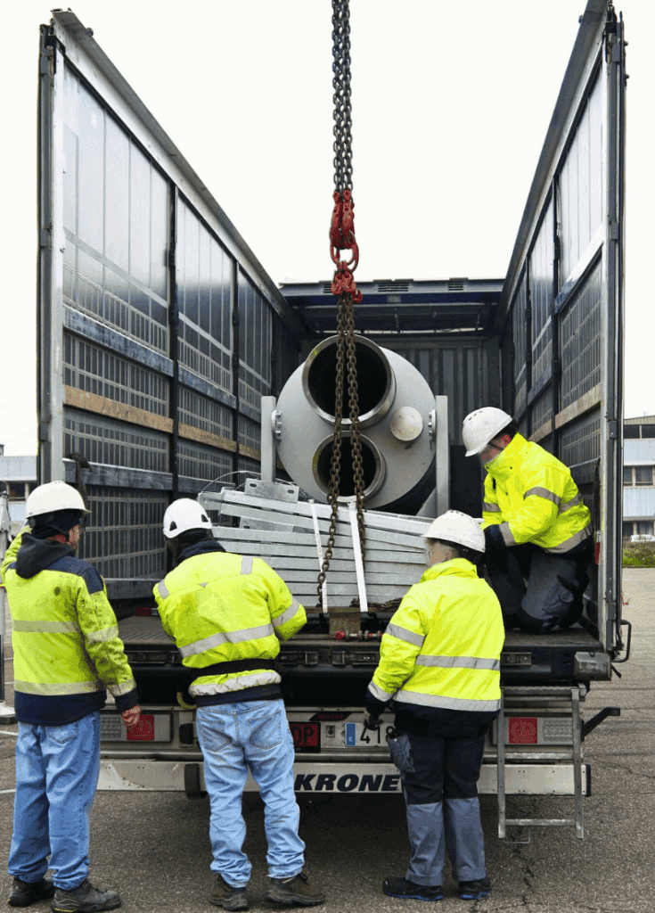 4 personnes en train d'analyser la situation suivante : une cheminée dans un camion prête à être grutée pour être sortie